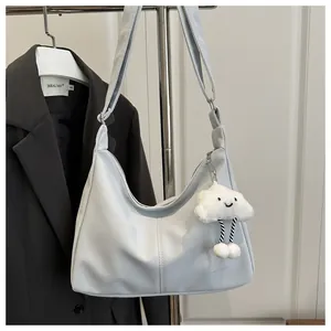 Chic light blue crescent shoulder bag with cloud charm styled on a black blazer