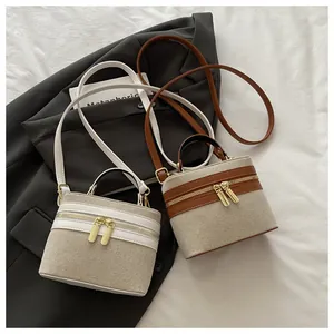 Detail view of two canvas and leather vanity bags on grey blazer with gold zippers