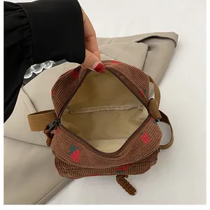 Detail view of the brown corduroy mini crossbody bag with red strawberry pattern and inner lining