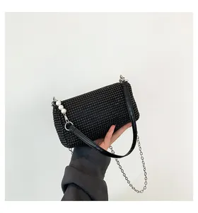 Detail of black rhinestone handbag with pearl accents and silver chain strap