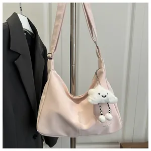 Detail of light pink hobo bag with adjustable strap and plush cloud charm on white wall