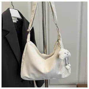 Close-up of cream white Hobo shoulder bag with plush cloud charm and TIDELINES logo