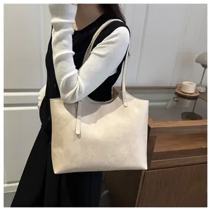 Close-up of cream-colored tote bag with textured faux leather and gold fashion lettering
