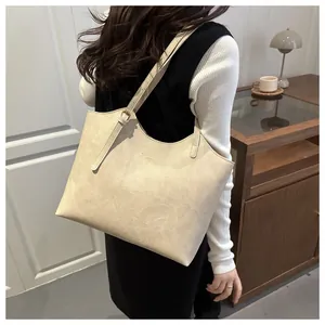 Detail of cream shoulder bag showing the textured cracked leather and gold buckle