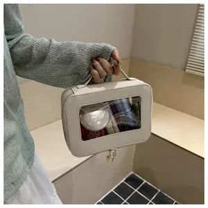 Detail view of cream PU leather cosmetic bag with clear window and golden zipper handle