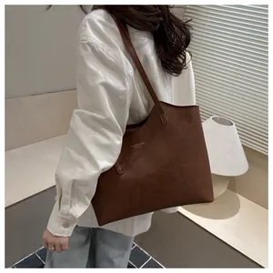 Detail shot of a dark brown large leather tote bag with gold logo for daily commuting