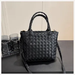 Detail of black woven leather handbag showing premium texture and gold hardware