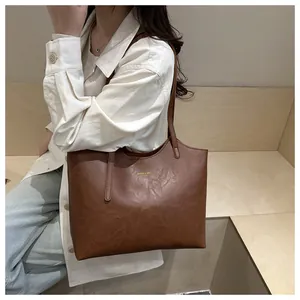 Macro shot of dark brown faux leather tote bag with gold lettering shown on model