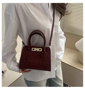 Détail d'un sac à main bordeaux à motif léopard avec fermoir rotatif en métal doré