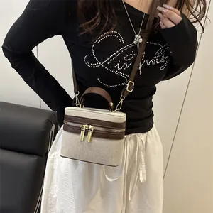 Chic beige canvas box bag with brown leather trim and golden hardware on a female model