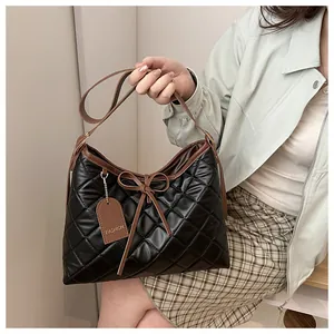 Detailed close-up of quilted nylon shoulder bag with leather bow and branded fashion tag