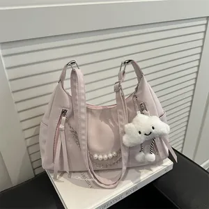 Pink PU leather tote bag with chain strap and cute cloud charm on books background