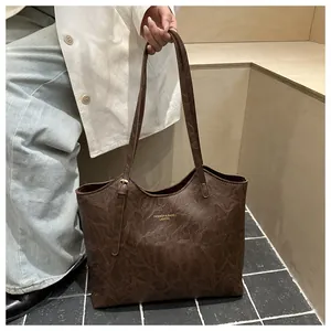 Detail of dark brown tote bag with marble texture and gold logo on neutral background