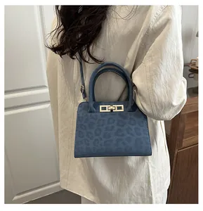 Détail du sac bleu à imprimé léopard avec boucle dorée et bandoulière sur une finition mate