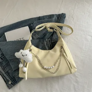 Light yellow crescent moon shoulder bag with pearl chain and cloud charm on bedsheet