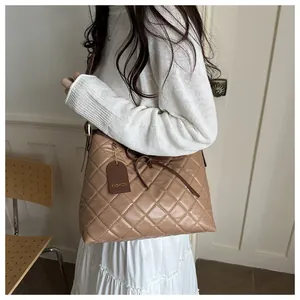 Detail of beige quilted shoulder bag with bow decor and leather fashion tag