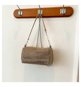 Detail of golden cylinder evening bag with sparkling rhinestones and pearl handle