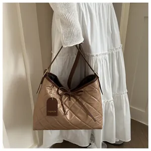 Detail showing checkered quilted pattern and delicate bow decoration on the khaki shoulder bag