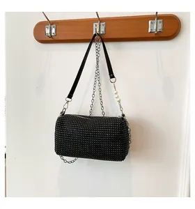 Detail of black rhinestone cylinder bag with metallic sparkles and decorative pearls