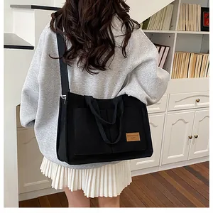 Vue arrière d'un grand sac cabas en toile noire avec double poignée et bandoulière