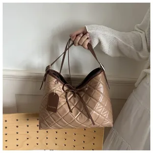 Detail of camel quilted crossbody bag with a brown ribbon bow and fashion brand tag