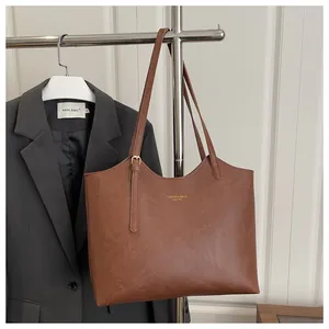 Detail of vintage brown tote bag showing smooth leather texture and gold lettering