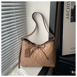 Detail of khaki quilted tote bag with ribbon bow and adjustable leather shoulder strap