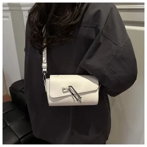 Petit sac bandoulière crème avec boucle argentée moderne porté par un mannequin