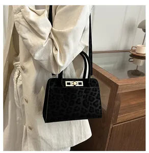 Détail d'un sac à main léopard noir vintage avec fermoir doré et deux poignées de transport
