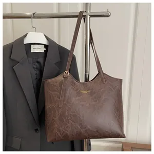 Close-up of a deep brown textured leather tote bag with gold lettering hanging on a hanger