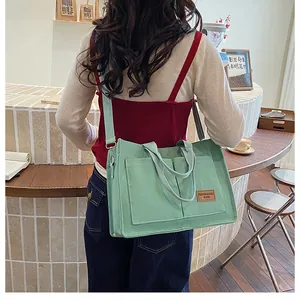 Vue arrière d'un grand sac en toile vert clair avec bandoulière réglable pour femmes