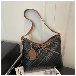 Close-up of black quilted tote bag with brown leather straps and a stylish bow detail