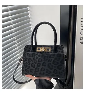 Détail d'un sac à main noir à motif léopard avec fermoir doré et poignée ronde