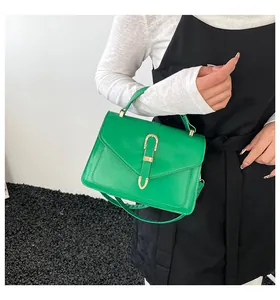 Close-up of bright green envelope square bag featuring a gold U-shaped metal clasp detail