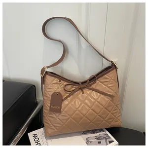 Detailed view of quilted tote bag with drawstring bow and fashion logo tag