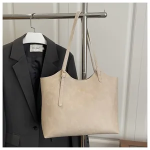 Close-up of beige tote bag with fine litchi texture and gold buckle detail