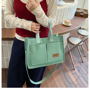 Détail du sac fourre-tout en toile vert menthe avec grandes poches et logo cuir