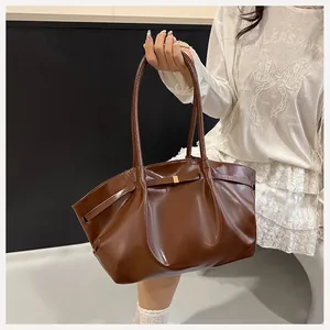 Dettaglio della borsa a secchiello marrone lucido con design pieghettato e fibbia dorata