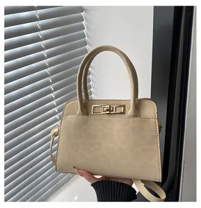 Détail du sac à main beige en daim avec texture léopard et boucle dorée à verrou rotatif