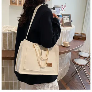 Détail du sac cabas en toile crème avec bandoulière réglable et poches frontales