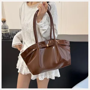 Dettaglio macro della borsa tote marrone lucida con fibbia metallica decorativa
