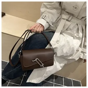 Gros plan d'un sac à bandoulière en cuir marron avec une boucle argentée en forme de trombone