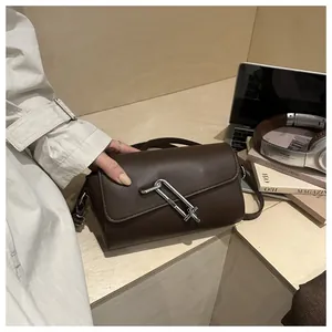 Vue détaillée du sac bandoulière en cuir mat marron foncé avec fermoir géométrique