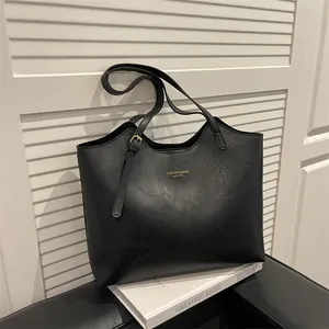 Minimalist black faux leather tote bag with gold logo for professional women