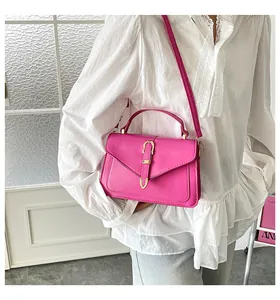 Model wearing a vibrant magenta crossbody square bag with elegant golden U-shaped buckle