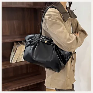 Dettaglio della borsa tote nera lucida con fiocco decorativo e finiture dorate