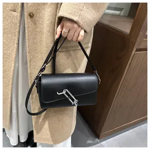 Détail d'un sac bandoulière noir avec une boucle métallique argentée en forme de trombone