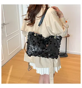 Détail du sac cabas à paillettes noires avec bandoulière chaîne sur un trench-coat chic