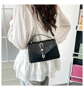 Model wearing a retro black leather crossbody bag with elegant gold U-shaped buckle detail