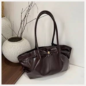 Dettaglio borsa tote in pelle verniciata marrone scuro con design a pieghe e fibbia dorata